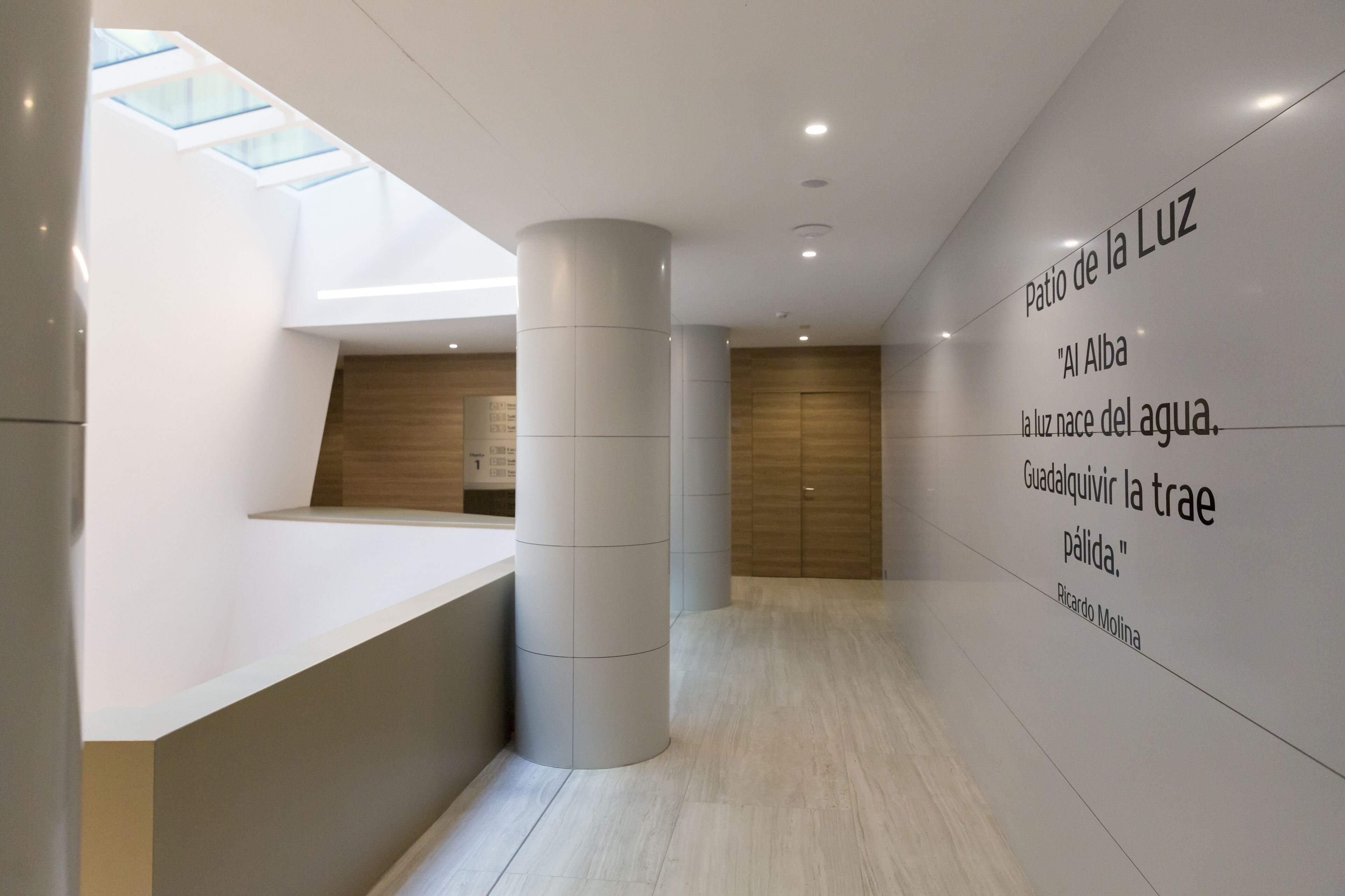 Un intérieur moderne comprenant un comptoir d’accueil, une grande colonne et un mur orné de texte.