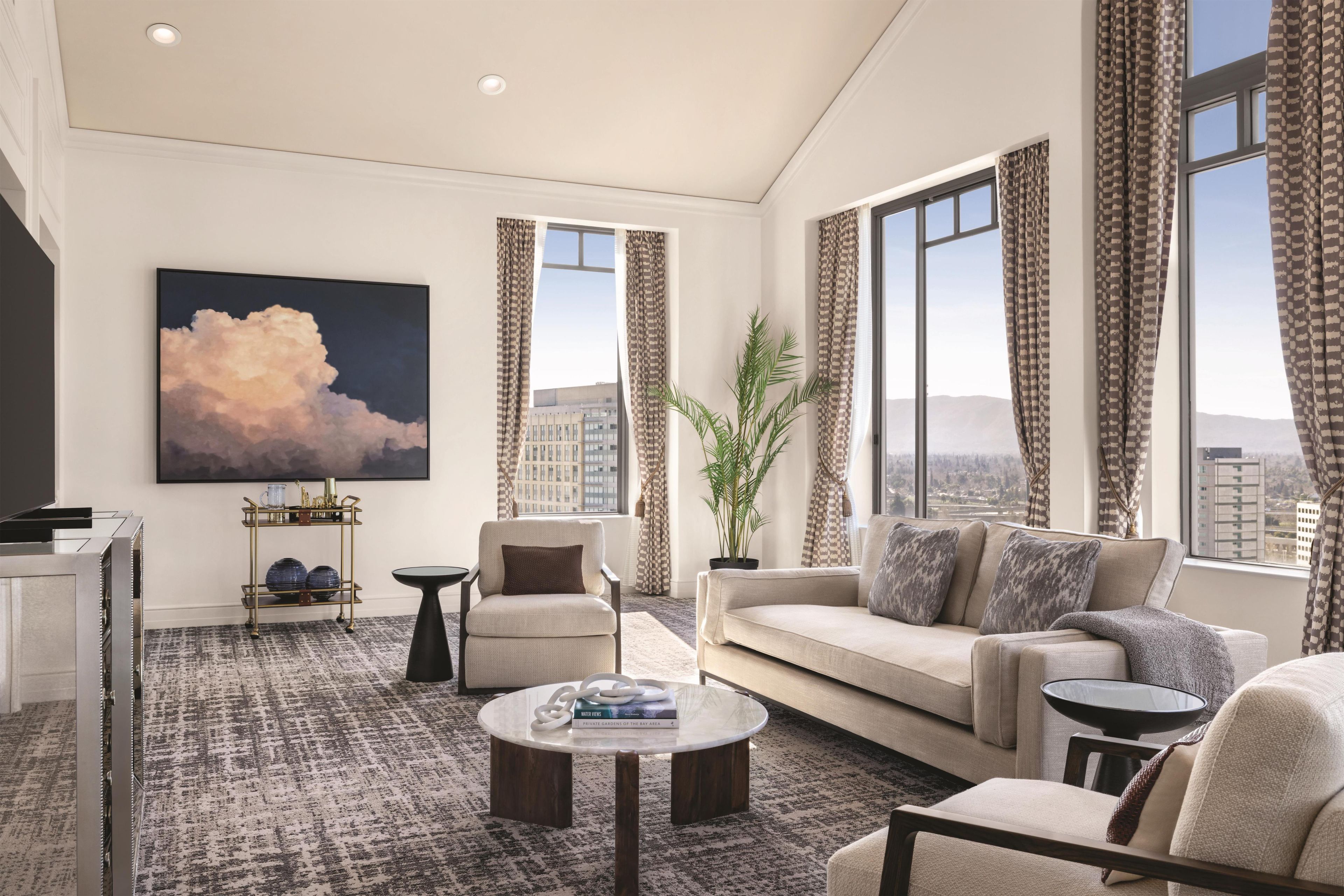 A modern living room with a sofa, armchairs, a coffee table, and a large painting.