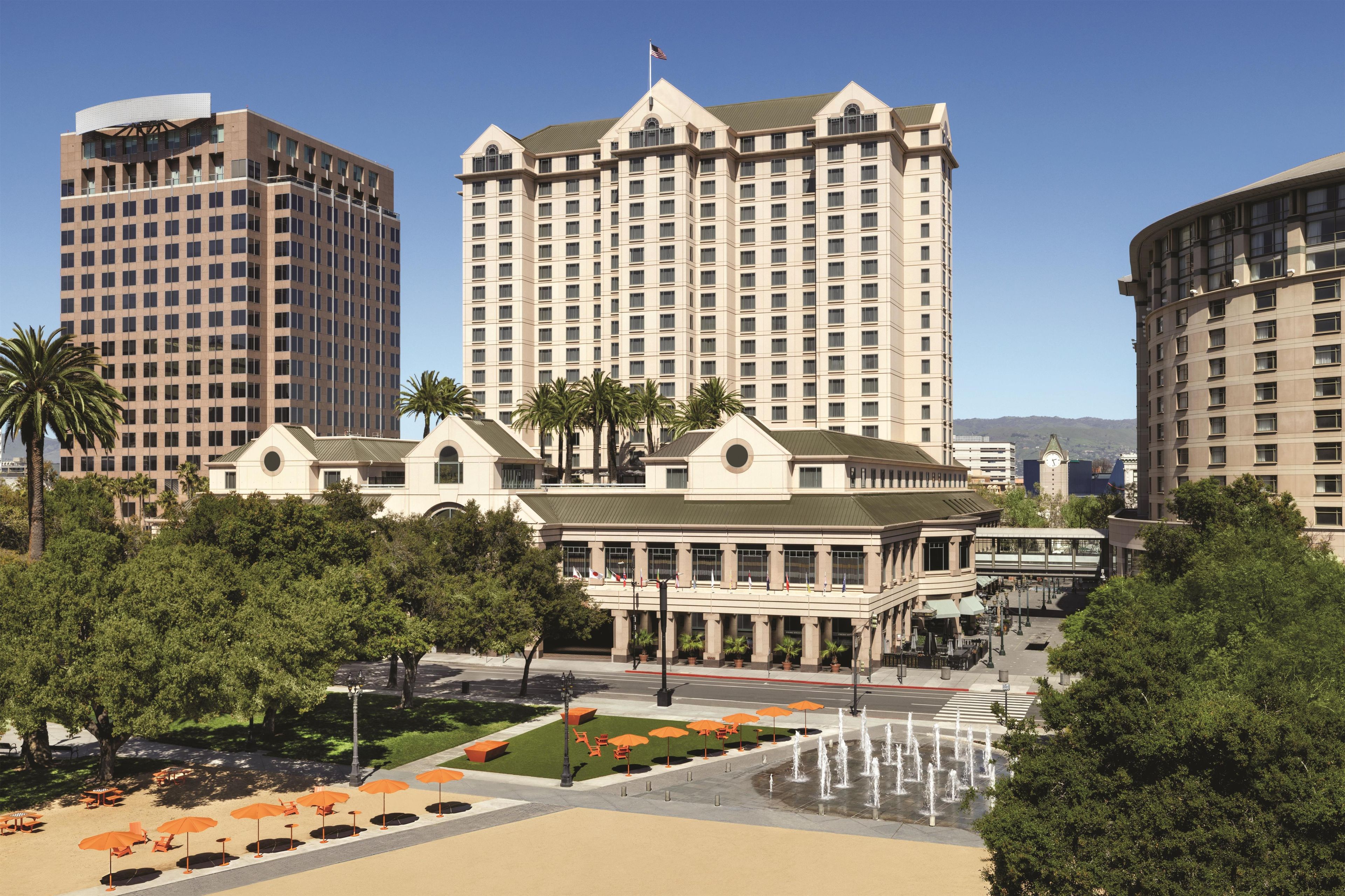 Een hotel met een centrale binnentuin, palmbomen en een fontein.