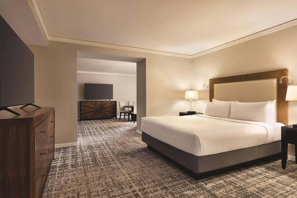 A hotel room with a large bed, a TV, a desk, and a chair.