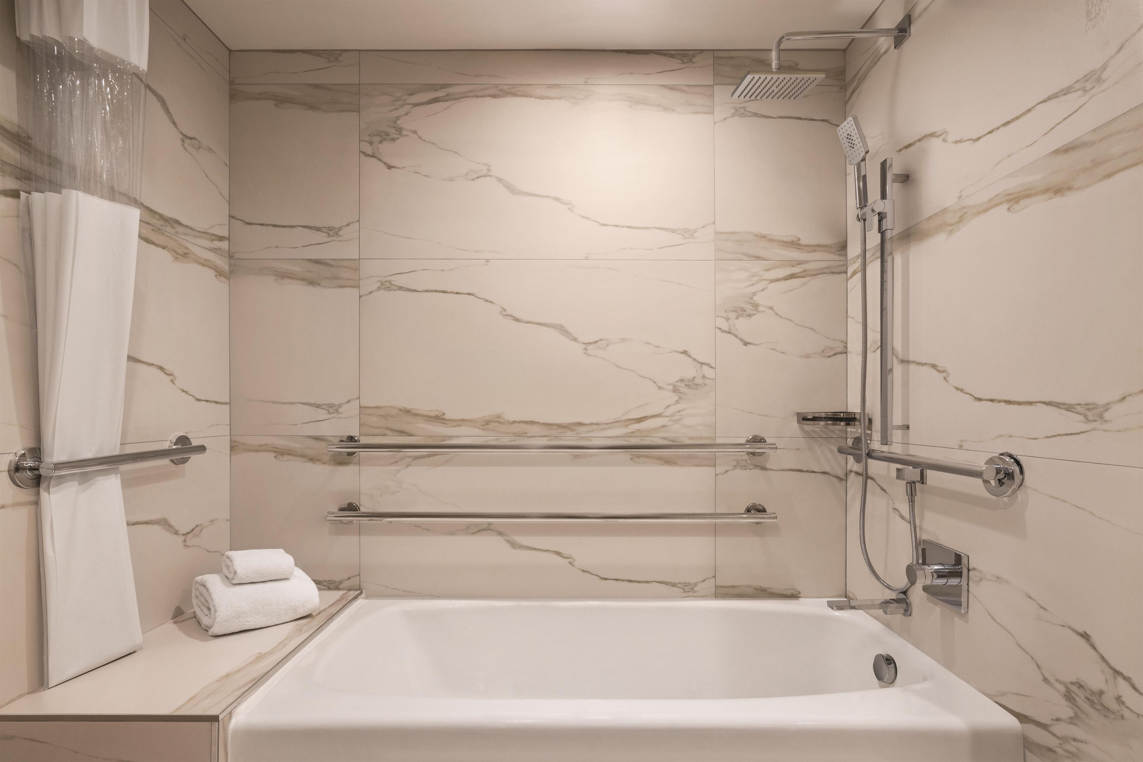 Une salle de bain avec un mur en marbre, une baignoire, une douche et un porte-serviettes.