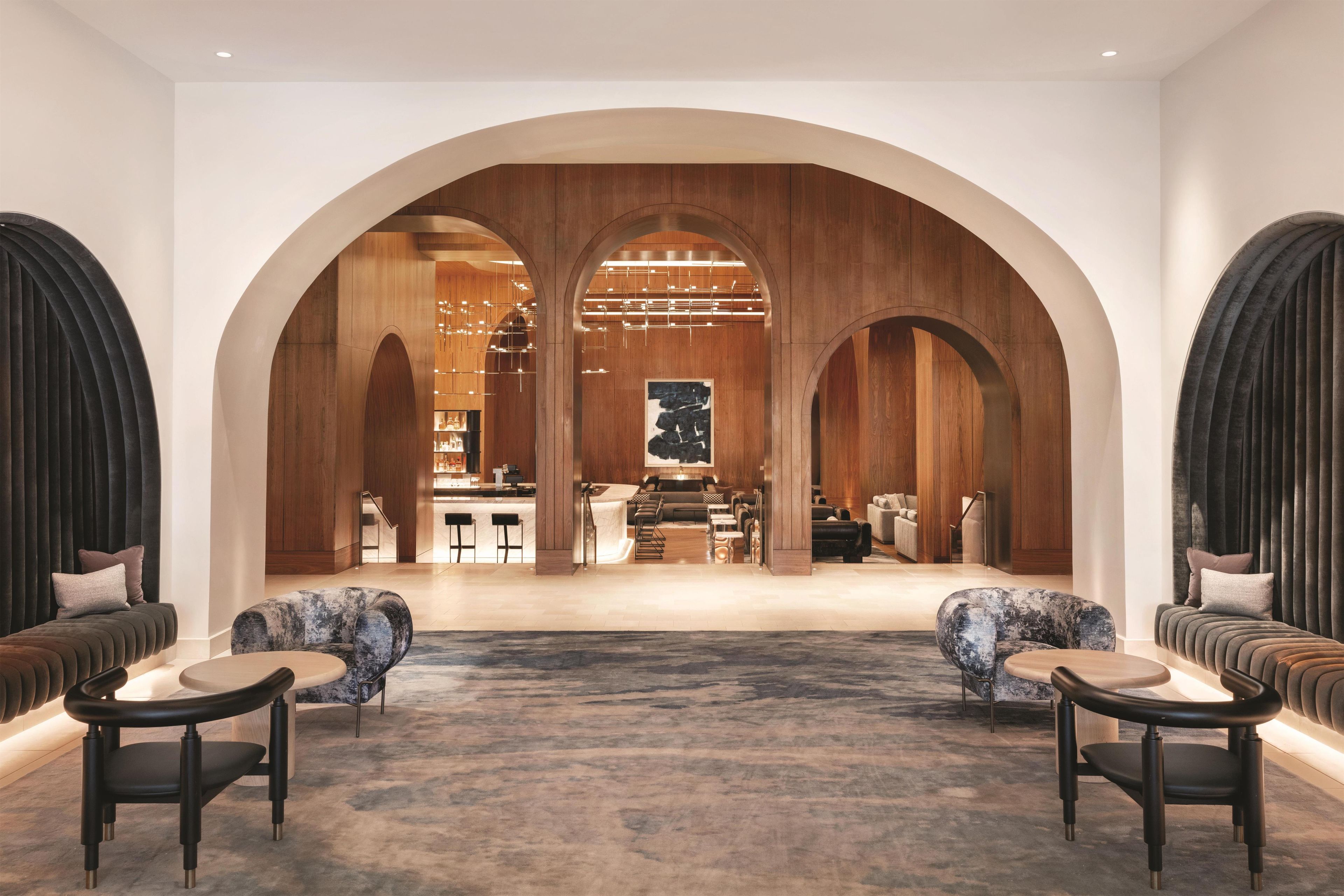 Un'ampia hall con un'area salotto centrale, archi in legno e un design d'interni moderno.