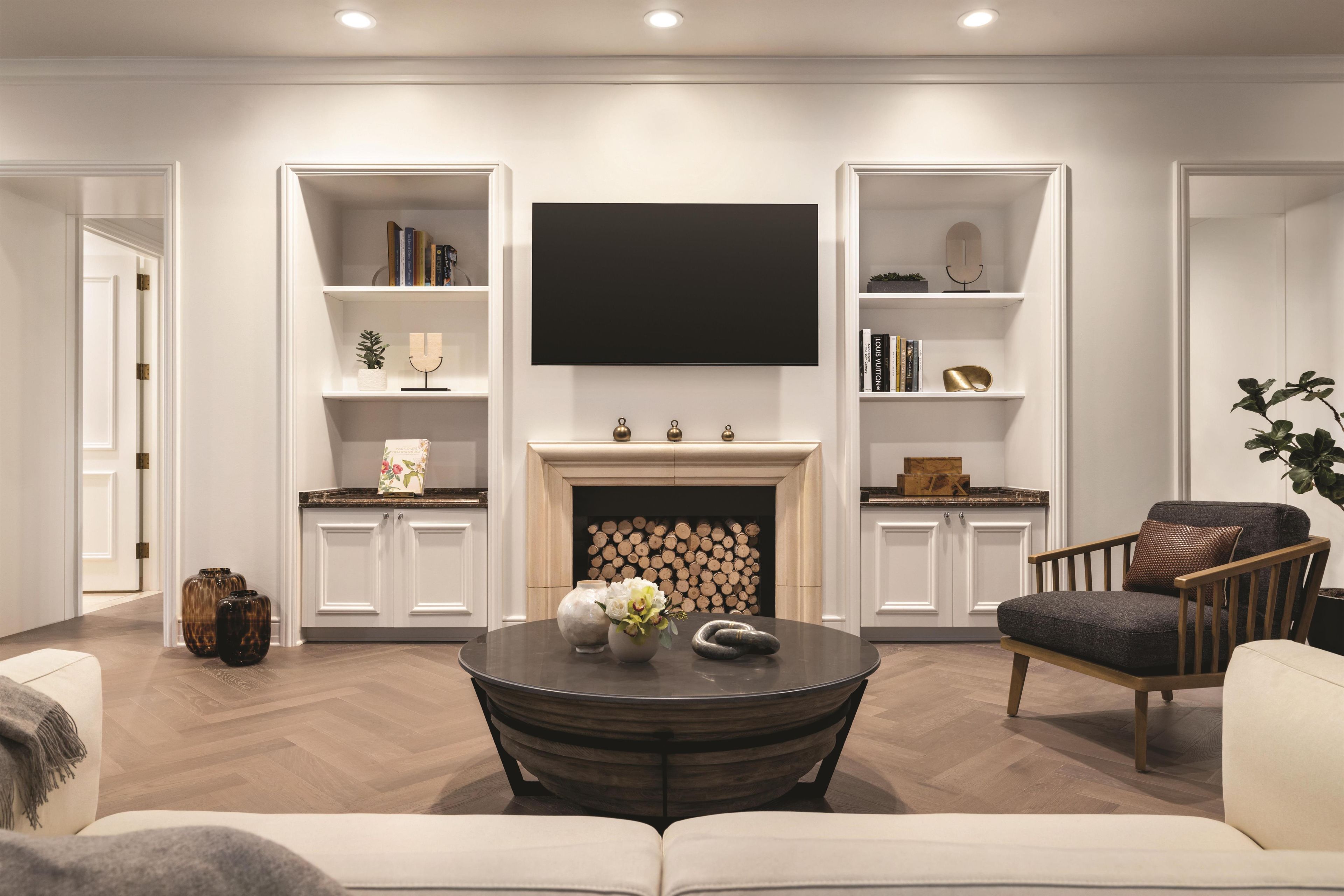 Una sala de estar con chimenea, un televisor de pantalla plana y estanterías empotradas.