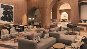 A modern hotel lobby with a large seating area, wooden paneling, and a staircase leading to the upper floor. - Signia by Hilton San Jose (San Jose)