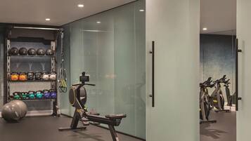 A modern gym with exercise equipment, a weight rack, and a mirrored wall.