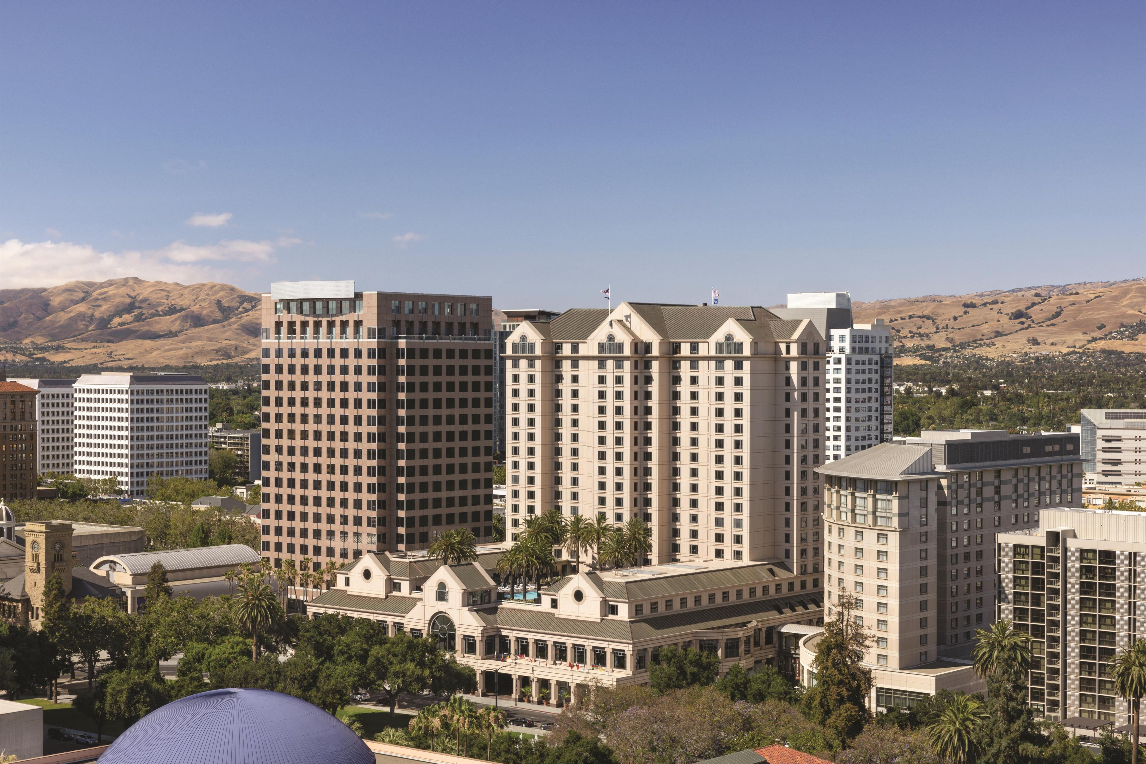 A hotel with multiple high-rise buildings, a central courtyard, and a mountainous backdrop.