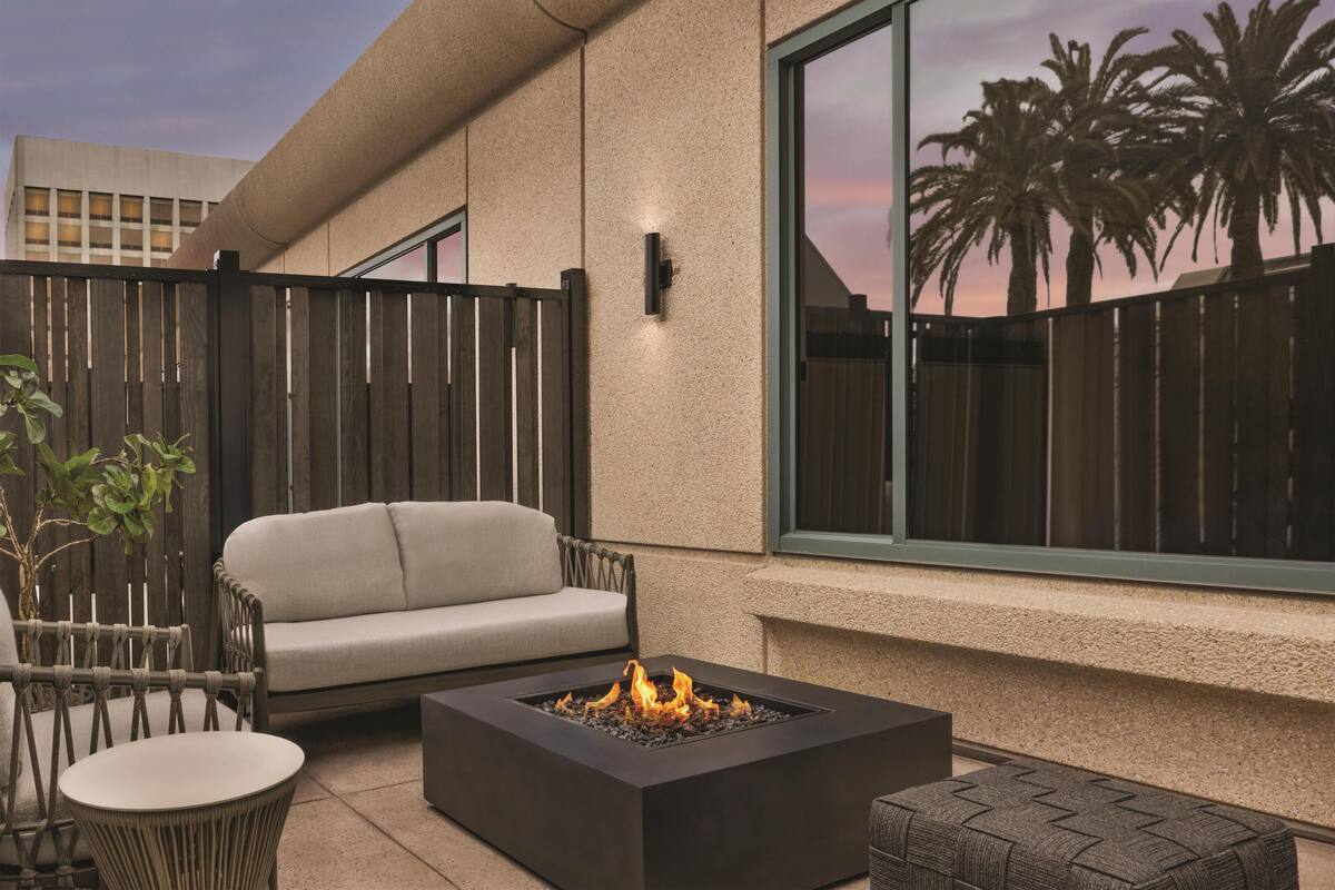A patio with a fire pit, a sofa, and a dining table.