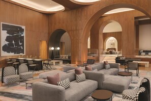 A modern lobby with a central seating area, a dining table, and a staircase leading to an upper level. - Signia by Hilton San Jose (San Jose)