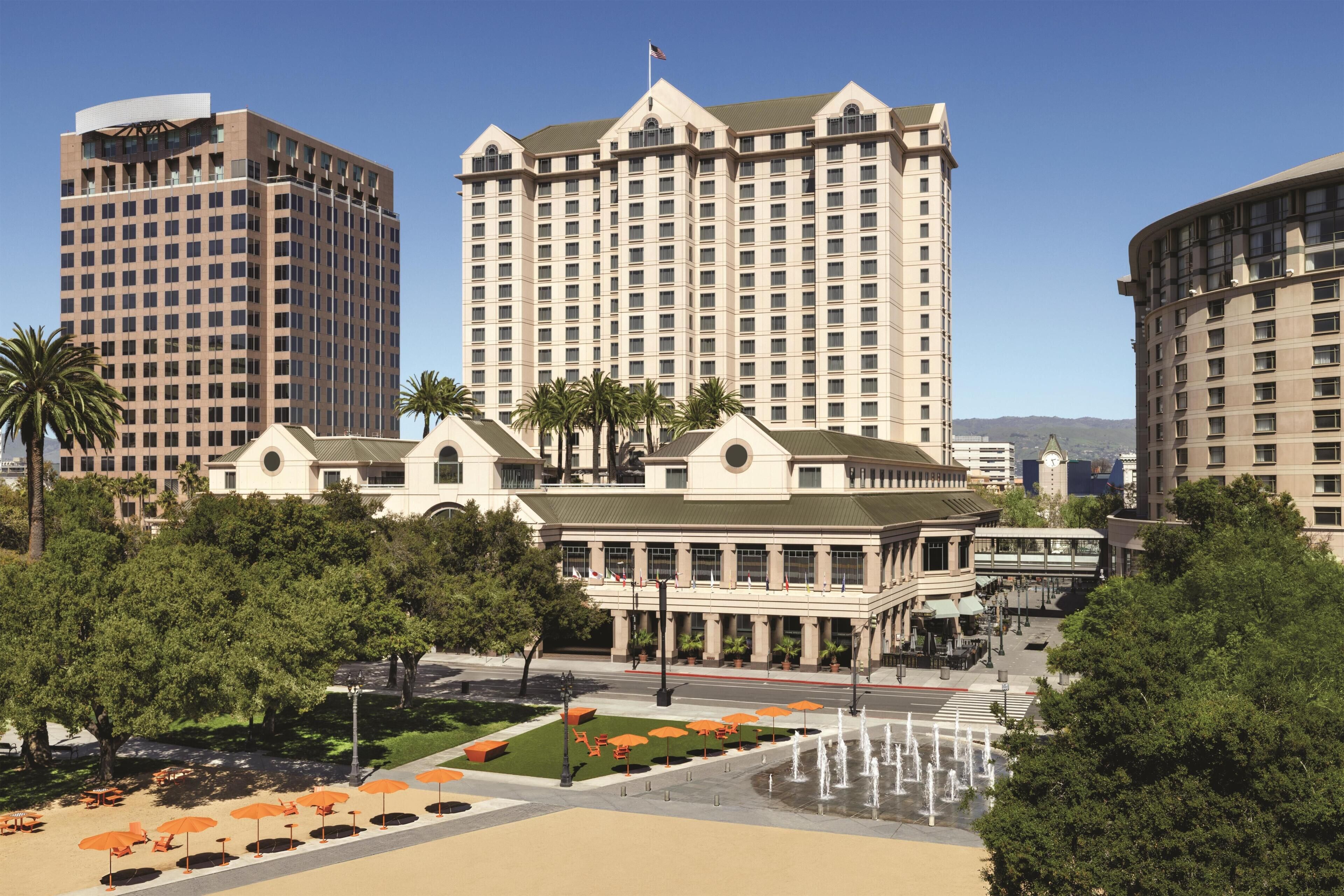 A hotel with a central courtyard, palm trees, and a fountain.