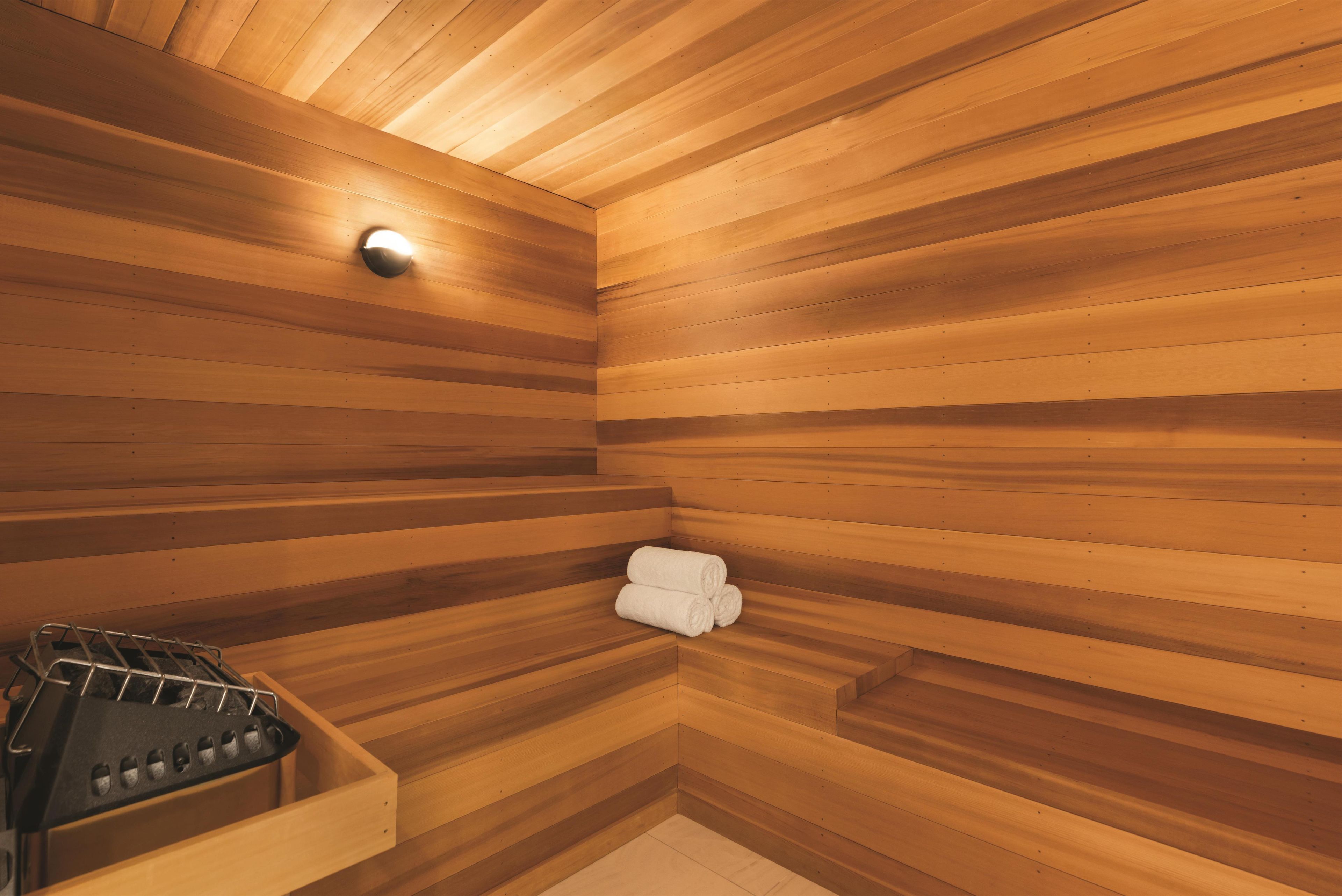 Una sauna con paredes de madera, un banco, una toalla y un calentador de sauna.