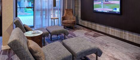 Een moderne hotelkamer met een groot flatscreen televisietoestel, comfortabele zitplaatsen en uitzicht op het omliggende landschap.