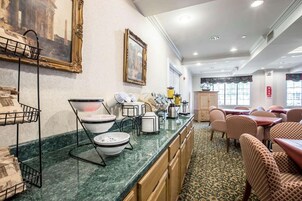 Comedor de hotel con mostrador de mármol, mesas, sillas y alfombra estampada.