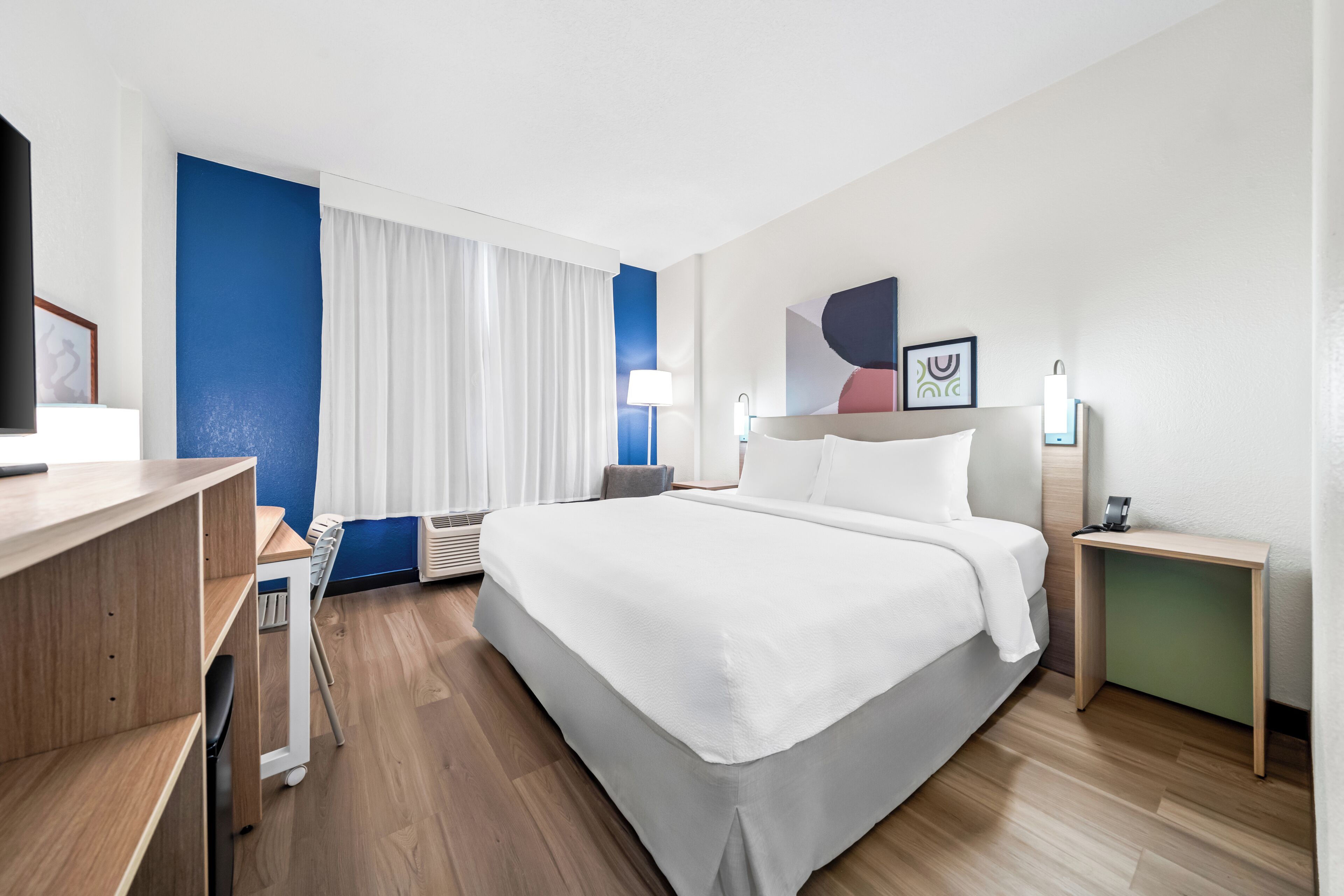 Een hotelkamer met een bed, nachtkastjes, een bureau en een stoel.