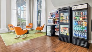 Un hall d’hôtel moderne doté d’un espace salon, d’une petite kitchenette et de distributeurs automatiques.