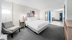 Une chambre d’hôtel avec un lit, une chaise, un bureau et une lampe.
