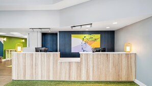 Un comptoir d’accueil au design moderne, avec un revêtement en bois et un tapis vert.