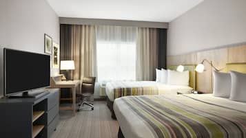 A hotel room with a flat-screen TV, a desk, two beds, a chair, and a large window with curtains.