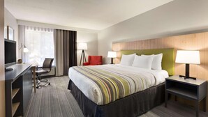 A hotel room with a bed, desk, chair, and lamps.