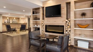 A modern living room with a fireplace, a flat-screen TV, and a dining area with a table and chairs.