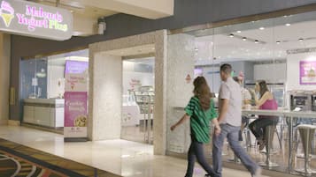 Una heladería de yogurt con un letrero que dice "Malena's Yogurt Plus" y un anuncio de "Cookie Dough".