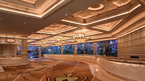 A spacious lobby with a curved reception desk, ornate ceiling design, and a large window offering a view of the outdoors. - Treasure Island TI Las Vegas - Handwritten Collection (Las Vegas)