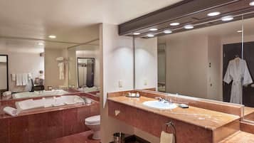 Un baño moderno con un espejo grande, lavamanos dobles y una bañera.