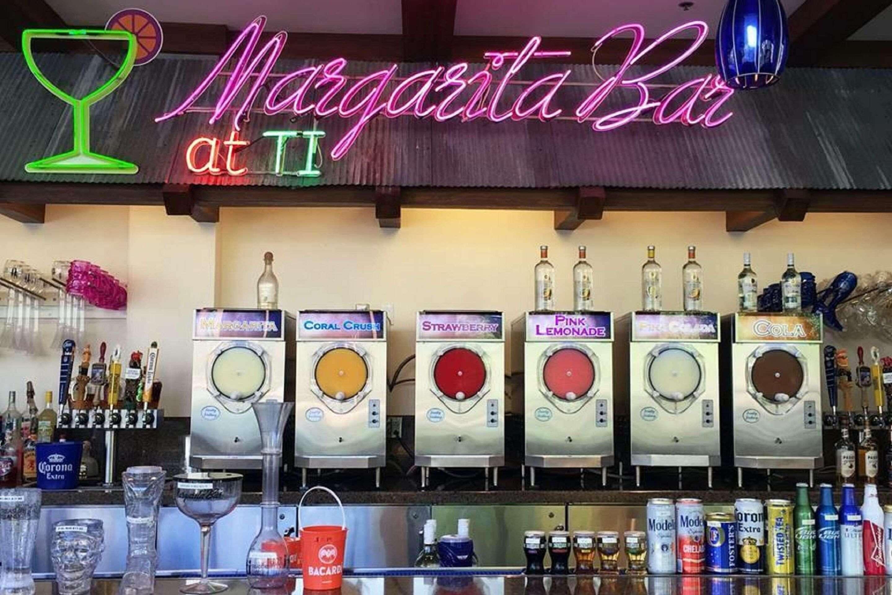 A bar named 'Margarita Bar at II' with multiple drink dispensers labeled with different beverages like Coral Crush, Strawberry, Pink Lemonade, and Cola.