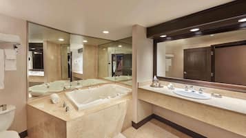 A modern bathroom with a large bathtub, a separate sink, and a mirror.