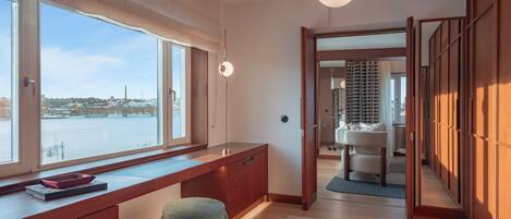 Una habitación moderna con un ventanal grande, un escritorio de madera y vistas a una masa de agua.