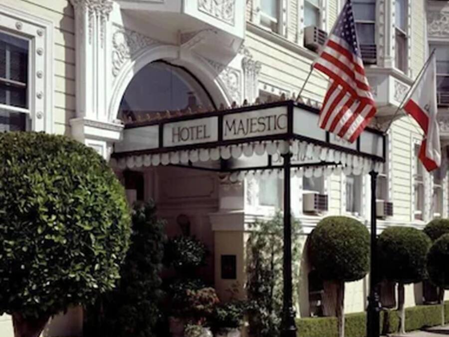 A hotel entrance with an American flag, a marquee sign, and well-manicured landscaping.