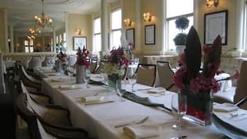 A long dining table set with white tablecloths, multiple place settings, and floral centerpieces.