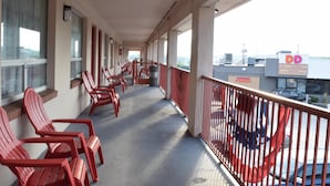 Un balcón con sillas rojas, vista a un Dunkin' Donuts y un edificio con un letrero 'DD'.
