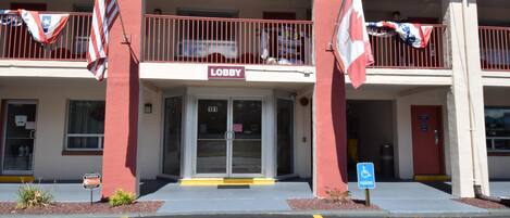 Un edificio con un letrero que dice 'Lobby', un letrero que dice 'Parking' y dos banderas.