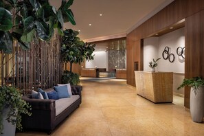 Un vestíbulo moderno con un sofá, una recepción y plantas decorativas.