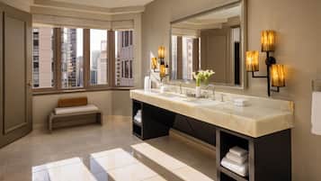 Un baño moderno con un espejo grande, lavamanos dobles y un banco.