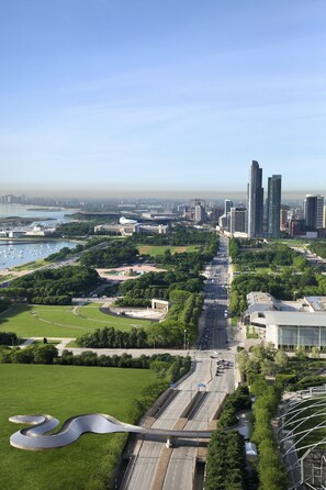 Un paisaje urbano con modernos edificios altos, un frente marítimo y una zona verde de parque.