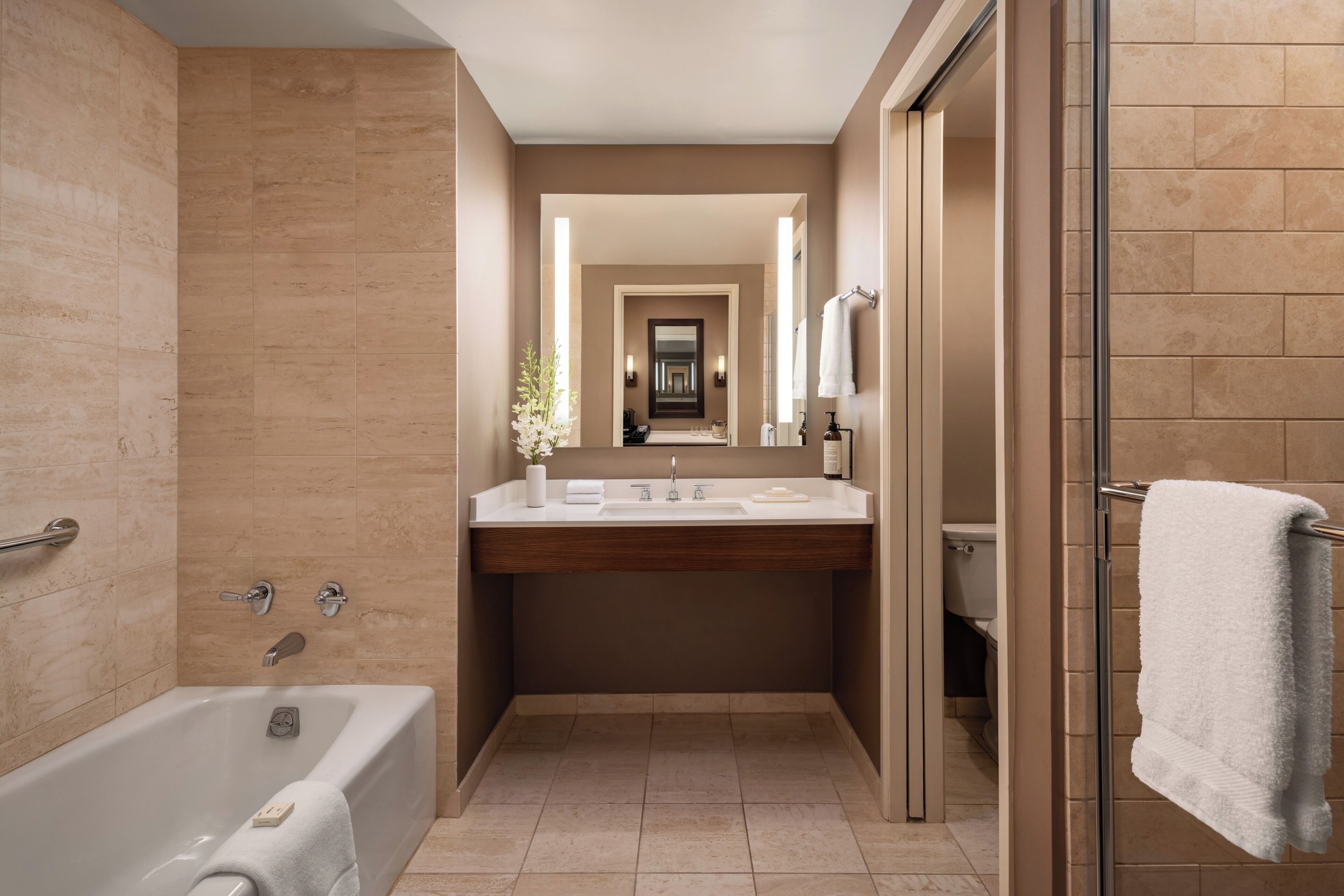 A modern bathroom with a bathtub, a vanity with a mirror, and a shower area.