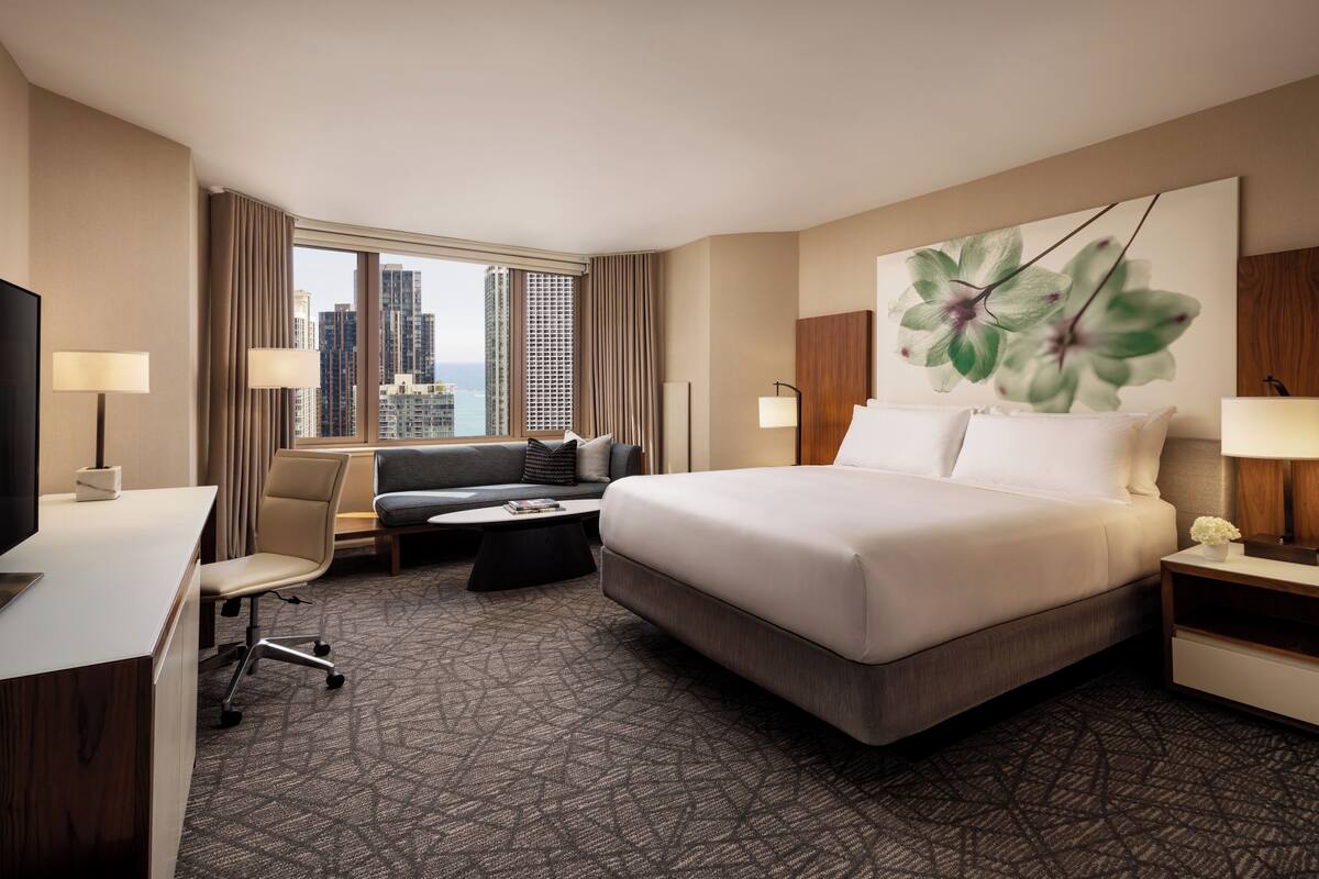 Habitación de hotel con una cama grande, un escritorio, un sofá y vistas a la ciudad.