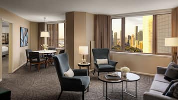A hotel room with a city view, a dining area, and a seating area with a table and chairs.
