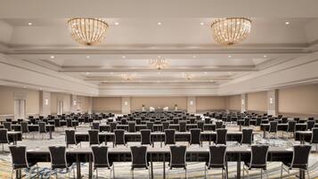 Une grande salle de conférence avec de longues rangées de tables et de chaises, des lustres et un éclairage encastré.