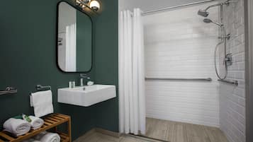 Un baño moderno con un lavamanos blanco, un espejo y una ducha con puerta de cristal.