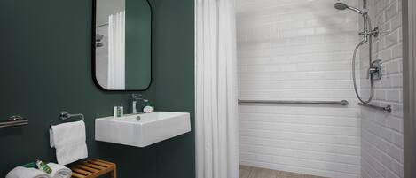 A modern bathroom with a white sink, a mirror, and a shower with a glass door.