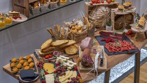 Una mesa de buffet con diversos alimentos, como pan, queso, carnes y frutas.