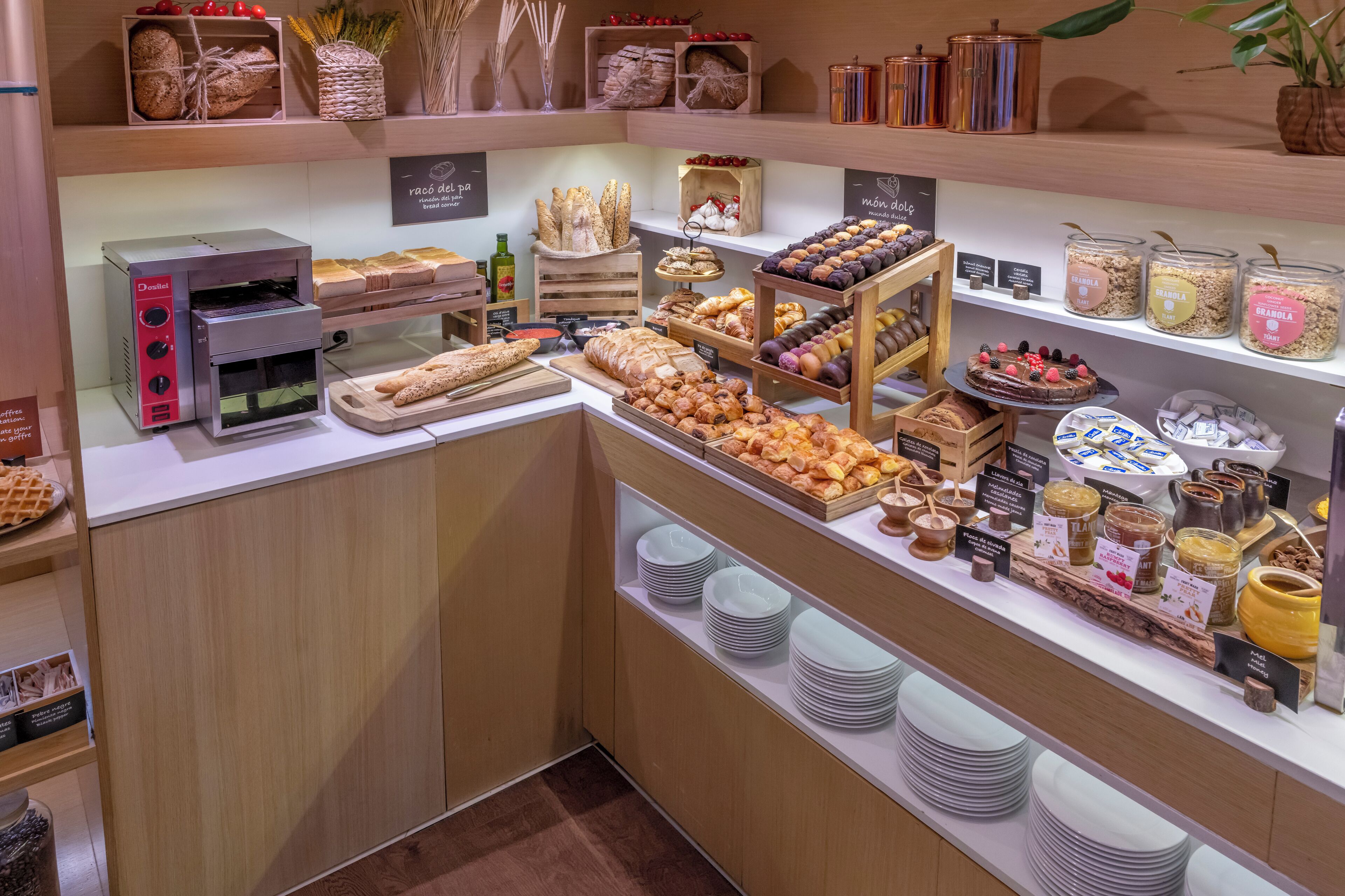 Un présentoir de boulangerie avec divers produits de pâtisserie, une machine à café et des pots de confitures et de pâtes à tartiner.