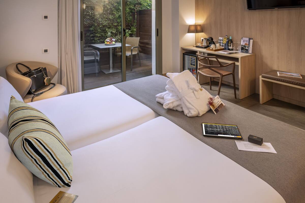 A hotel room with a bed, a desk, a chair, and a view of the outdoors.