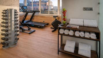 A gym with exercise equipment, a treadmill, and a wall with towels.