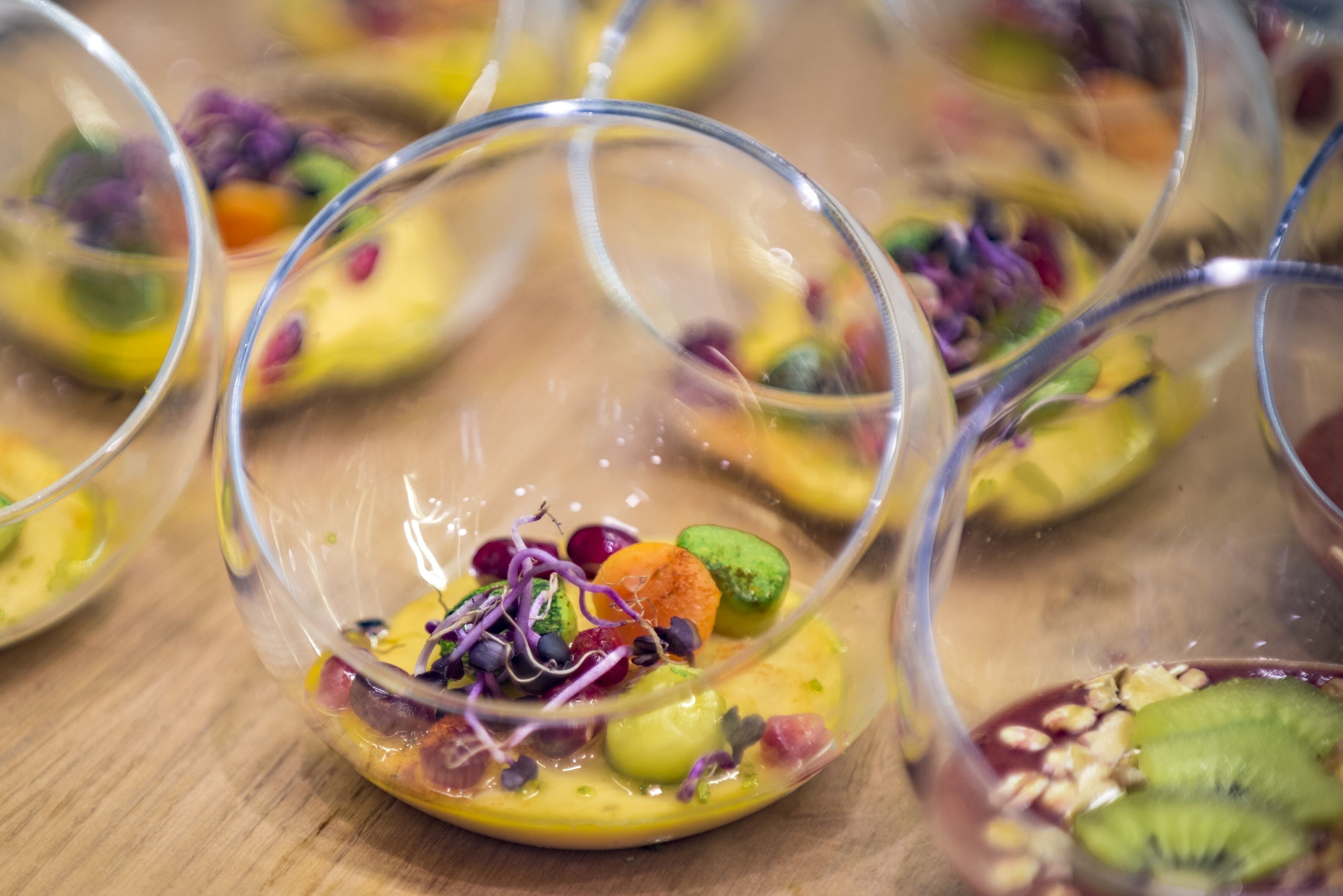 A dessert presentation with various fruits and nuts in clear glass bowls.