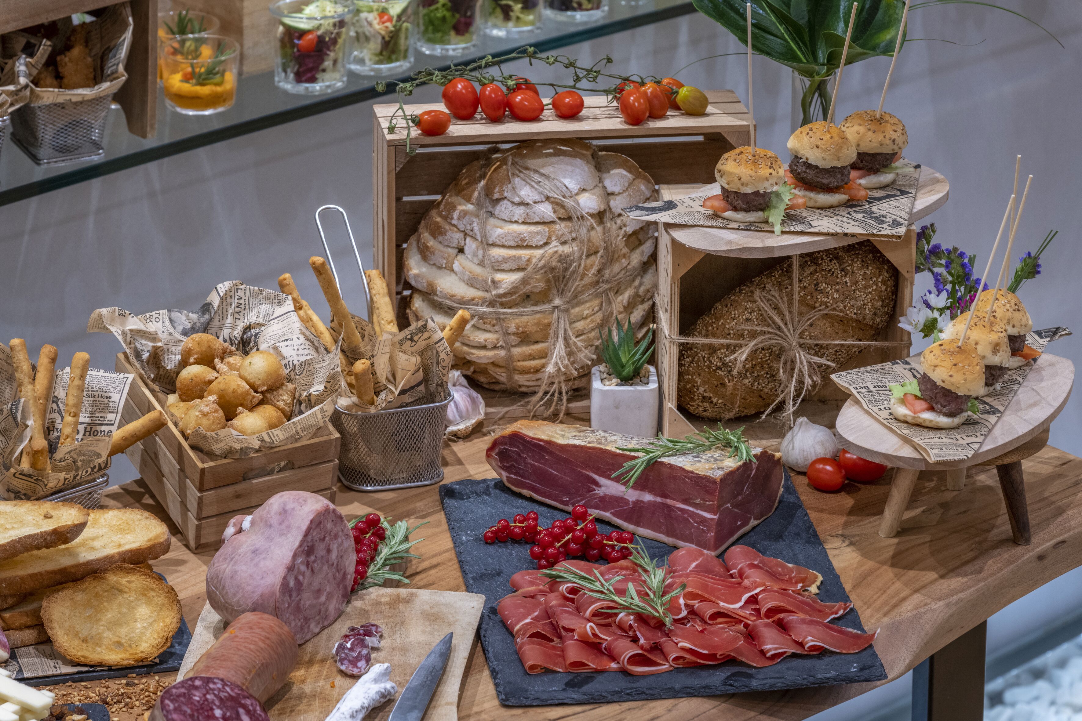 Verschiedene Speisen, darunter Brot, Fleisch und Gemüse, werden auf einem Holztisch präsentiert.
