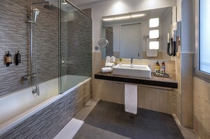 A modern bathroom with a glass-enclosed shower, a large mirror, a sink, and a toilet.