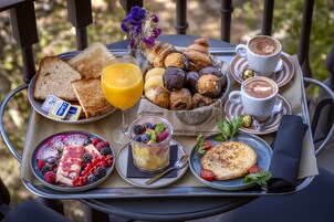 A tray with breakfast items including toast, croissants, pastries, fruit, and beverages.